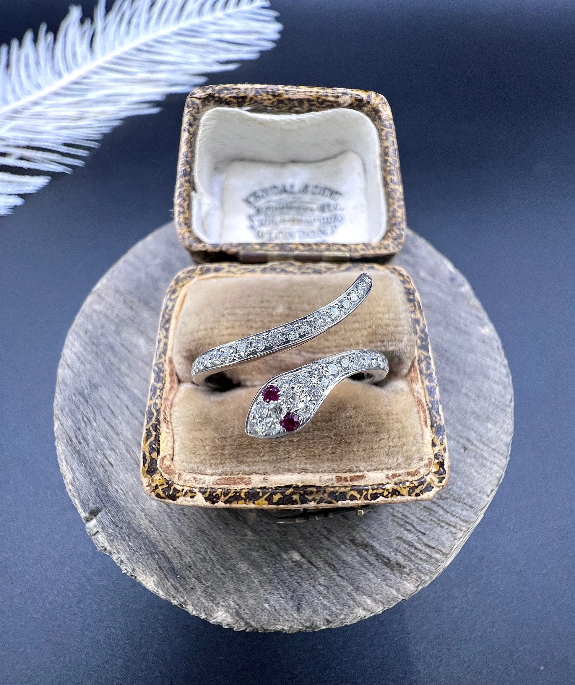 A white gold snake ring set with diamonds and with ruby eyes, in an antique ring box