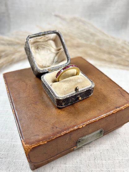 A yellow gold ruby channel set eternity band, in an antique ring box