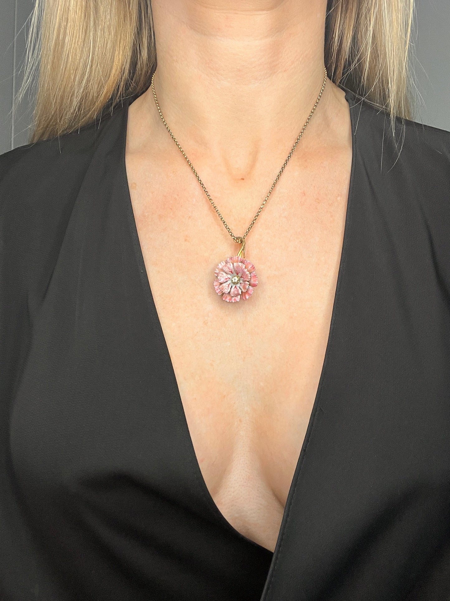 A pink enamelled flower pendant with a diamond centre, in yellow gold, modelled with a chain