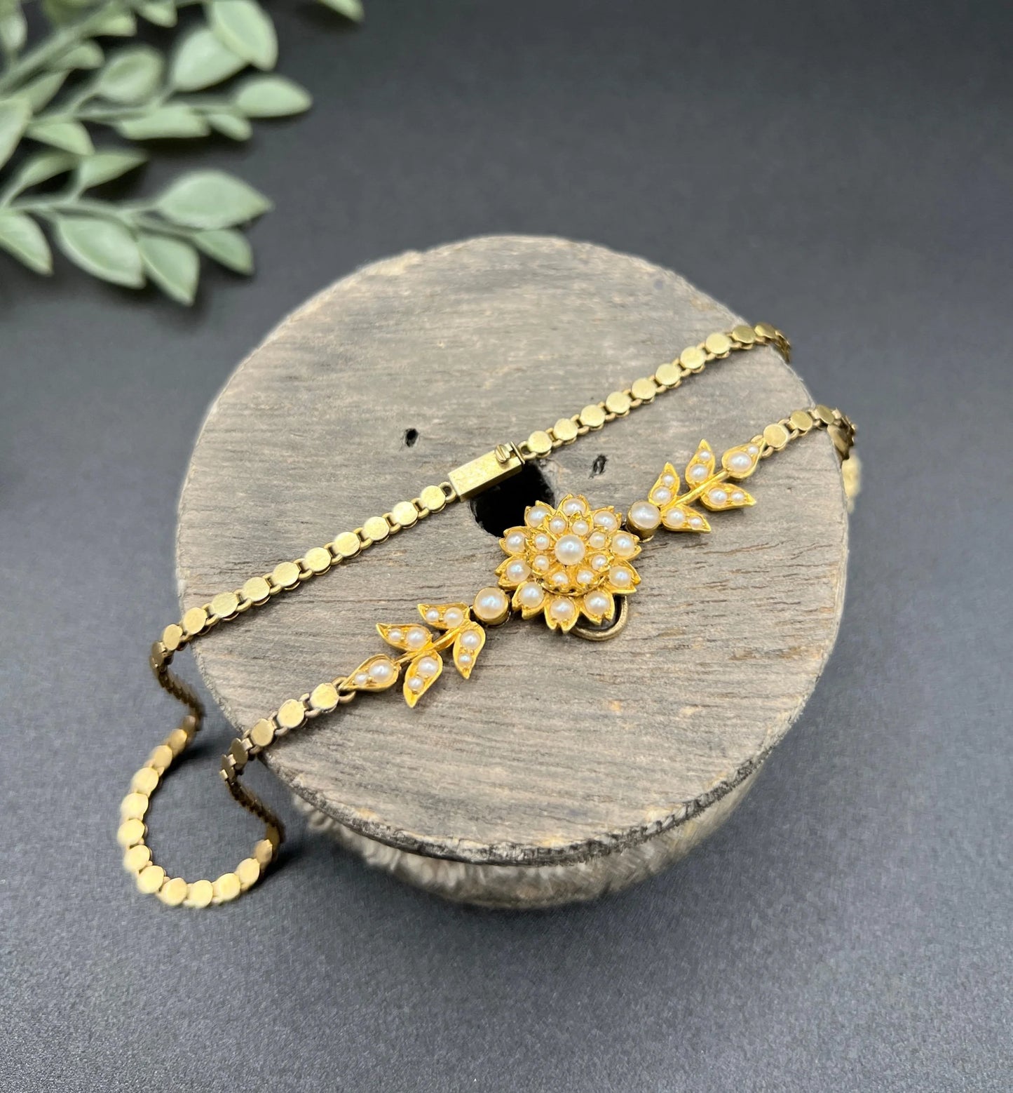 A yellow gold pearl floral necklace with integrated chain