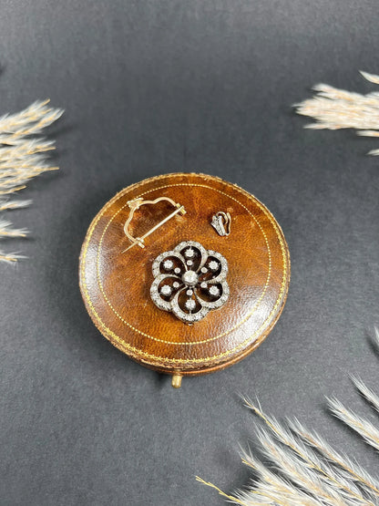 A floral design diamond set pendant/brooch on an antique brown jewellery box