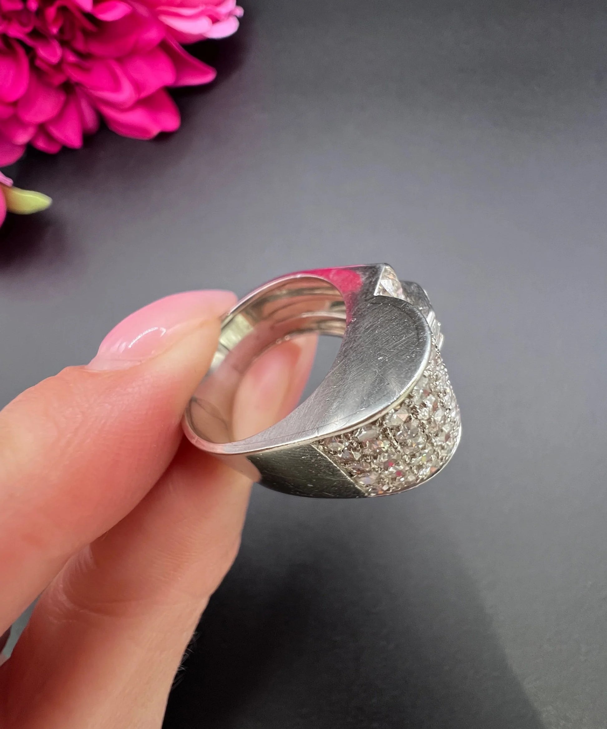 A round diamond tank style cocktail ring in platinum, held in a hand