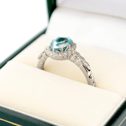 An oval aquamarine and round diamond cluster ring in white gold, in a ring box