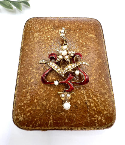 A floral pendant in yellow gold with seed pearls and red enamel