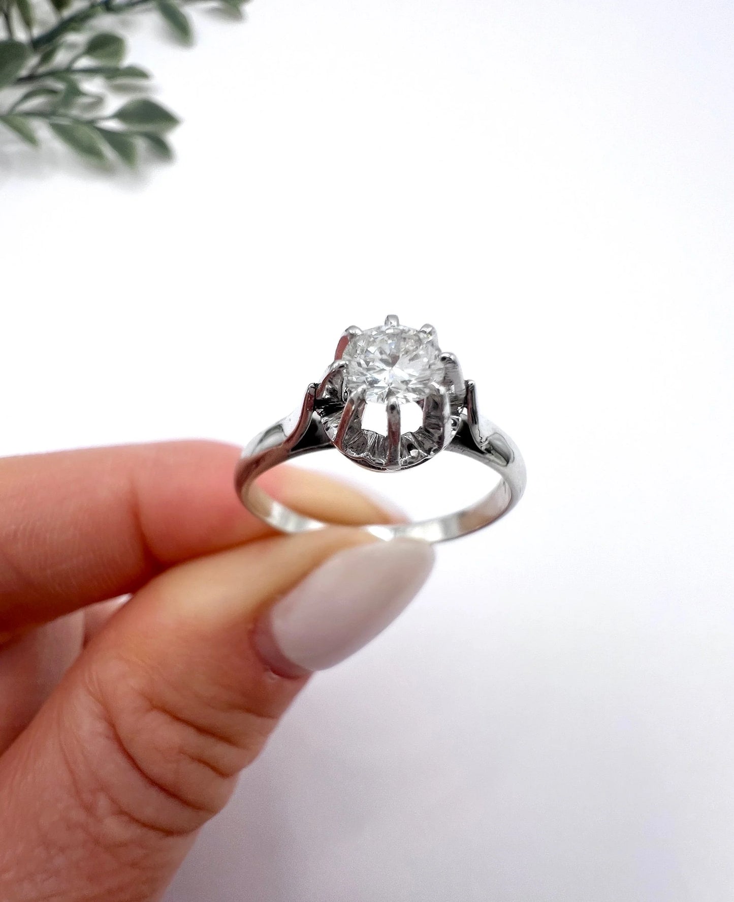 A solitaire round diamond ring in white gold, held in a hand