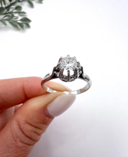 A solitaire round diamond ring in white gold, held in a hand