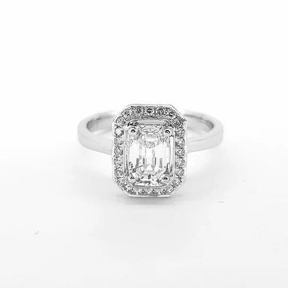 Emerald Cut Diamond Cluster Ring; featuring a central 0.87 carat emerald-cut diamond surrounded by brilliant cut diamonds, in 18ct white gold