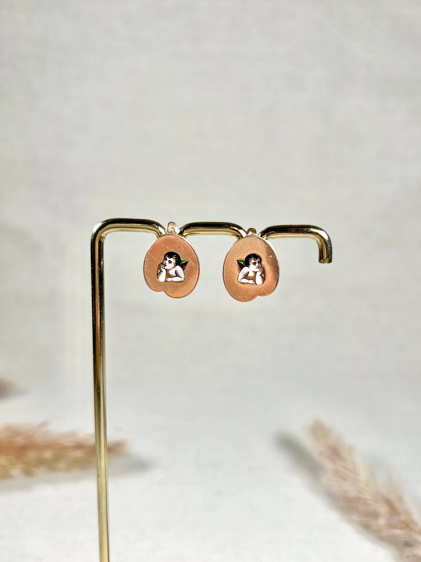 A pair of art palette shaped gold earrings with enamelled cherubs