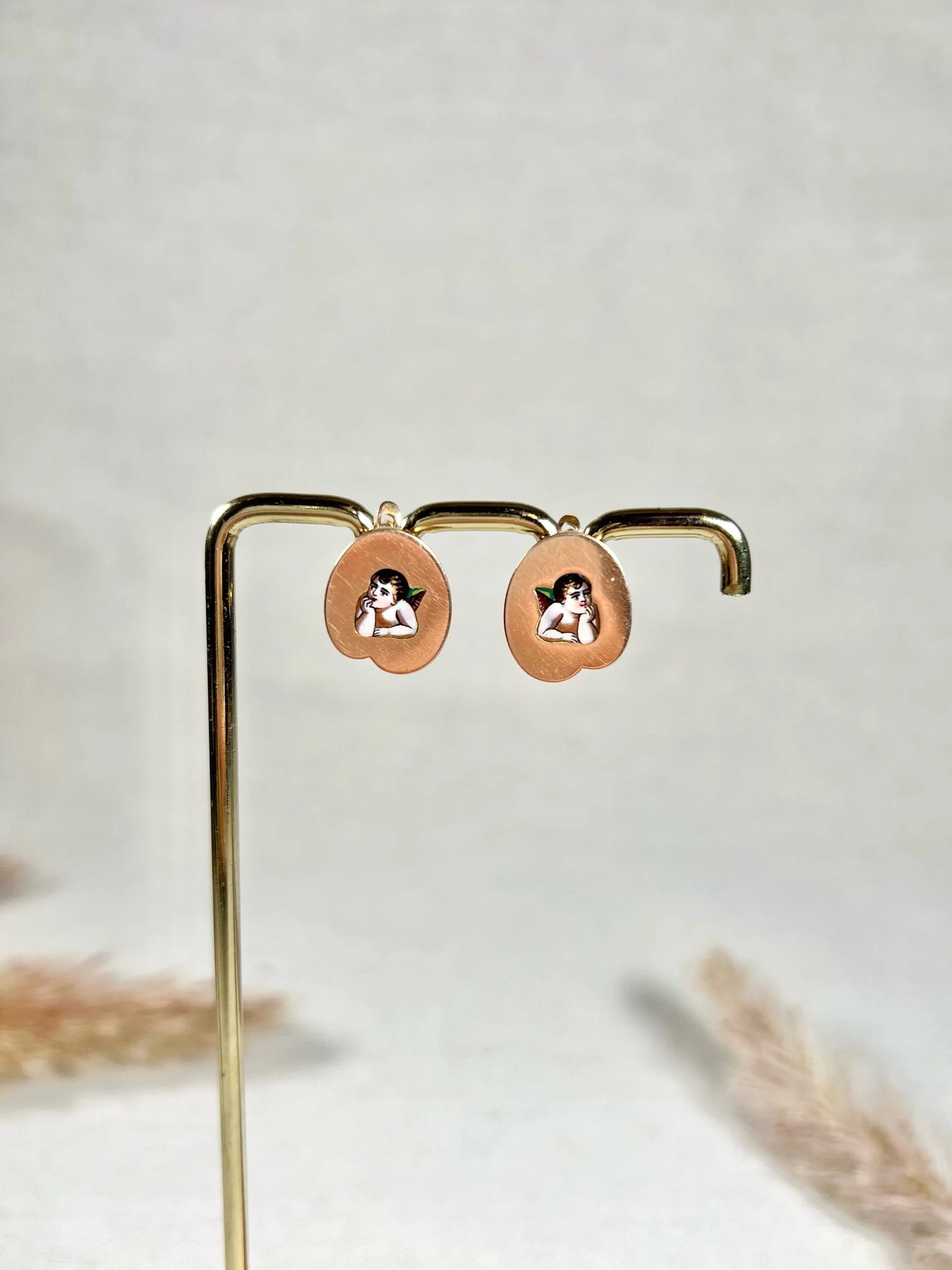 A pair of art palette shaped gold earrings with enamelled cherubs