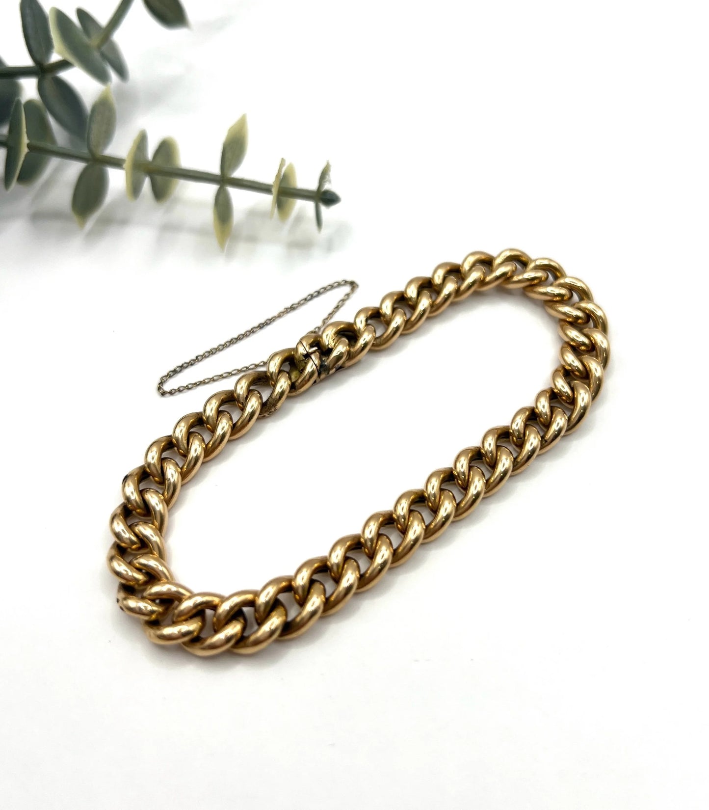 A curb link bracelet in yellow gold, on a white background