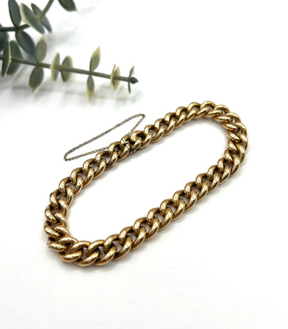 A curb link bracelet in yellow gold, on a white background