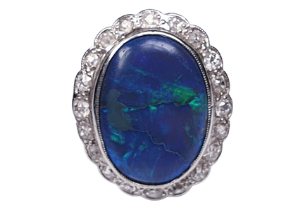 Vintage Black Opal and Old Cut Diamond Oval Cluster Dress Ring; featuring a large oval black opal surrounded by 0.60cts circular old-cut diamonds. Mounted in 18ct white gold. English, Circa 1940s