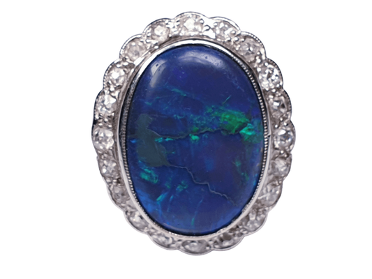 Vintage Black Opal and Old Cut Diamond Oval Cluster Dress Ring; featuring a large oval black opal surrounded by 0.60cts circular old-cut diamonds. Mounted in 18ct white gold. English, Circa 1940s