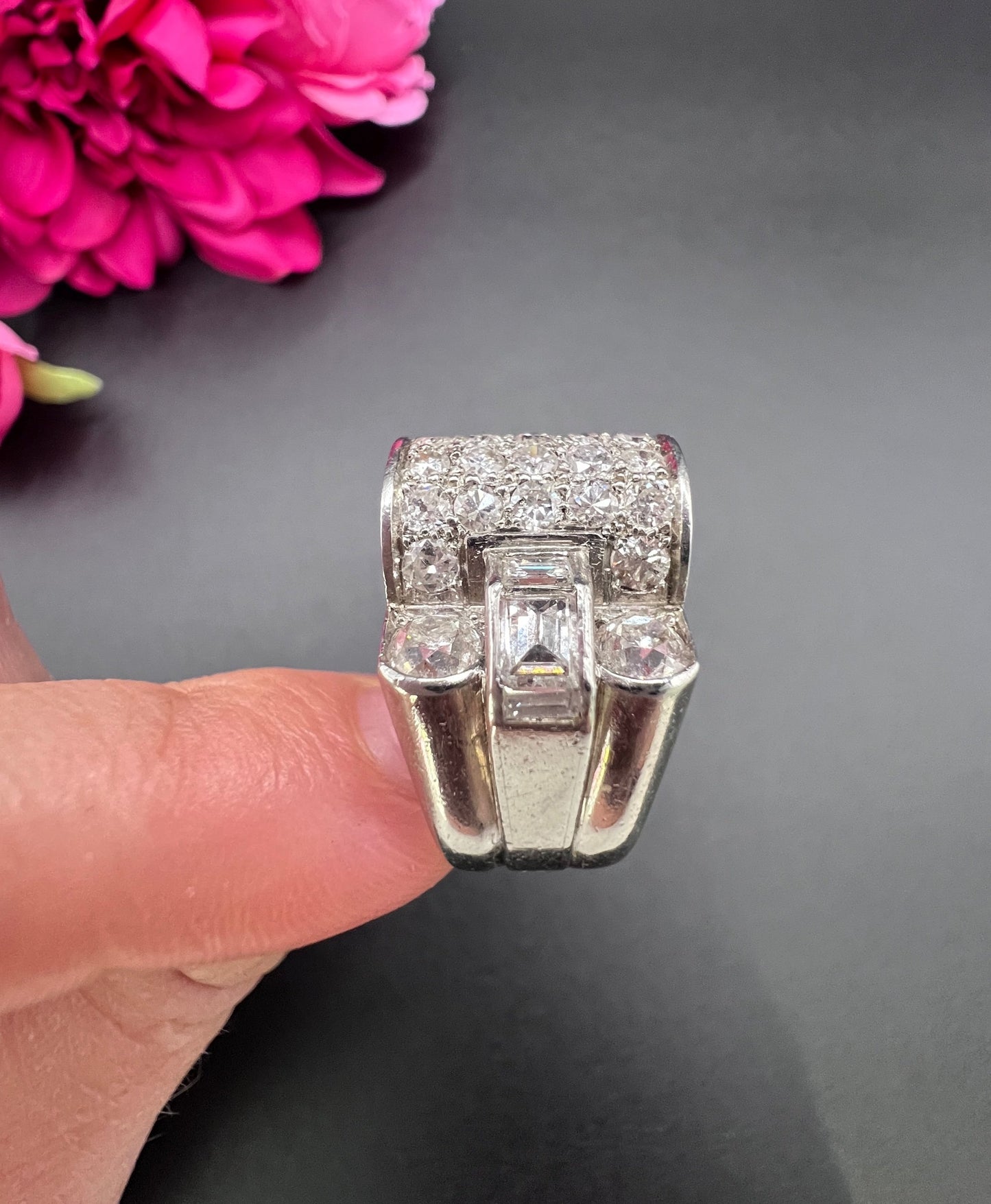 A round diamond tank style cocktail ring in platinum, held in a hand