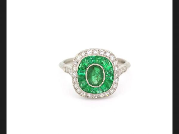 Vintage Emerald and Diamond Calibre Set Ring; Oval cut emerald encompassed by diamond and emerald halos, Set in Platinum