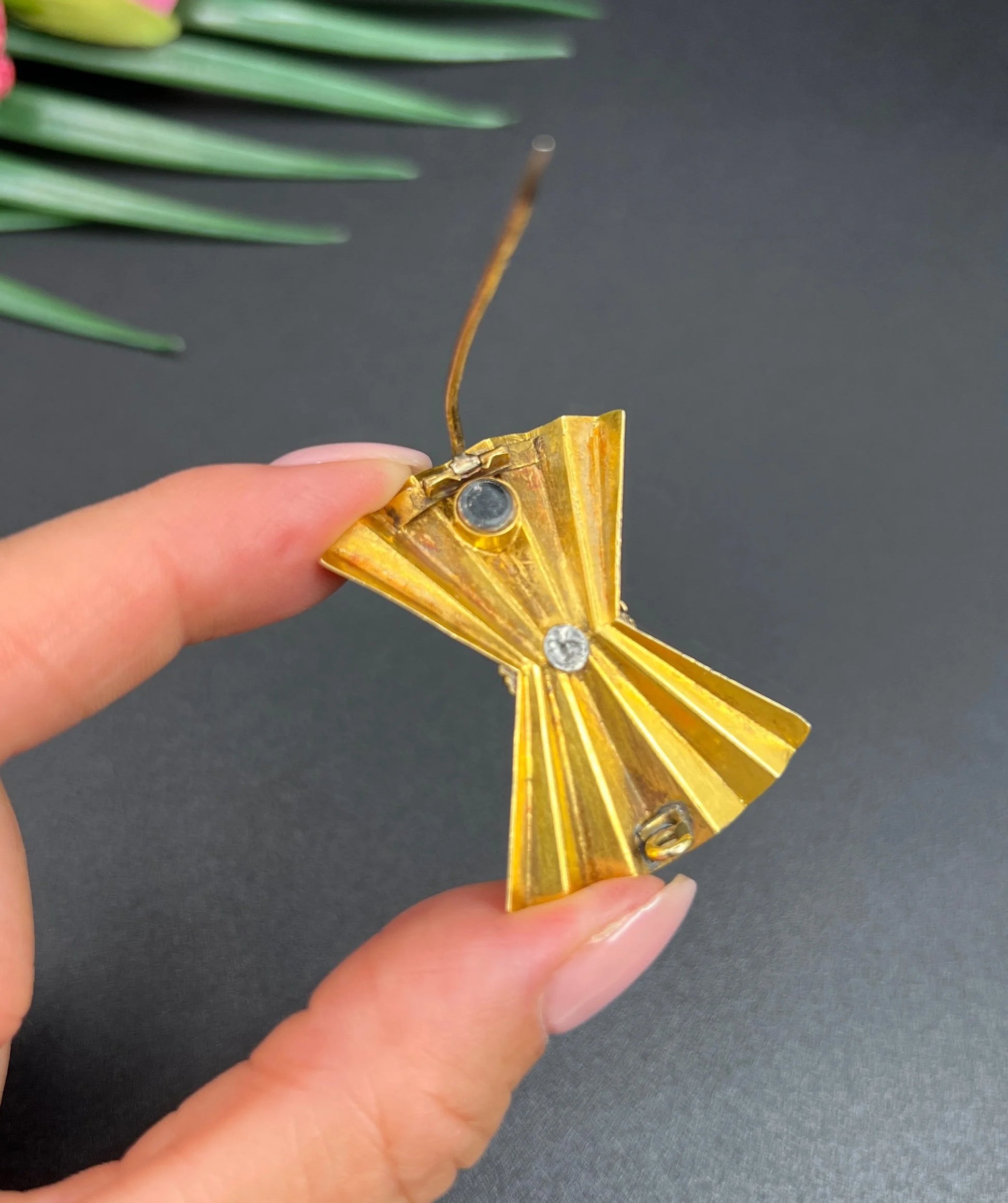A yellow gold bow shaped brooch with a small locket back