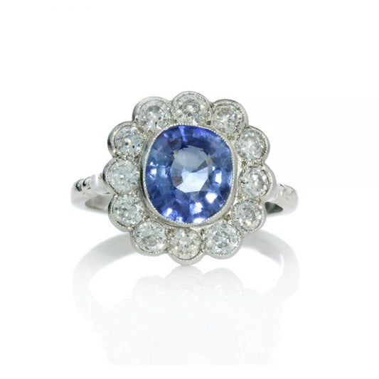 Natural Ceylon Sapphire and Diamond Floral Cluster Ring; featuring a 2 carat oval faceted Natural Ceylon sapphire surrounded by 1.20cts diamonds, in platinum and 18ct white gold