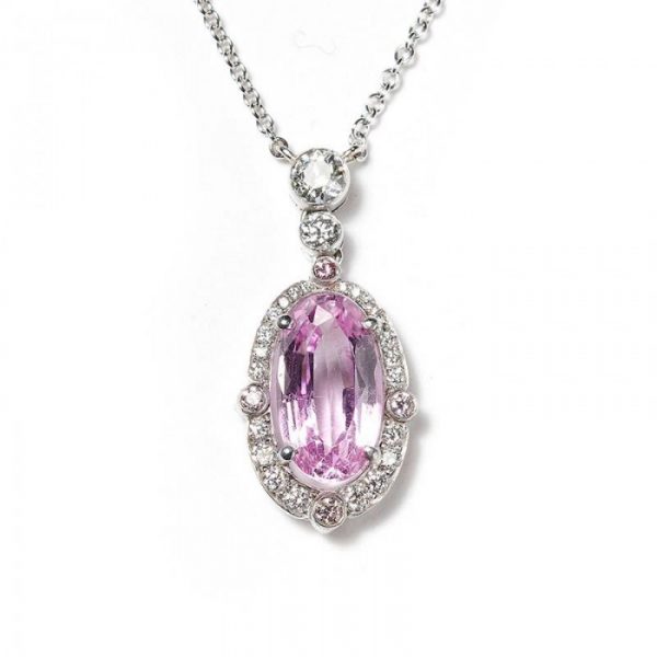 2.84ct Pink Topaz and Diamond Oval Cluster Pendant; set with a 2.84ct oval faceted pink topaz surrounded by a diamond halo, accented with pink diamonds on the quarters, and round brilliant-cut diamonds on the bale. Mounted in platinum and presented on a platinum trace chain.