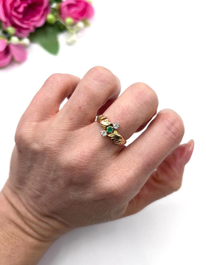 A three stone emerald and diamond ring in yellow and white gold, modelled on a hand