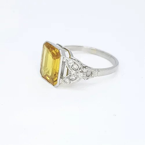 Emerald Cut Yellow Sapphire, Diamond and Platinum Ring; 3.20ct emerald-cut yellow sapphire accented with 0.15cts diamond set shoulders in fleur-de-lis deign