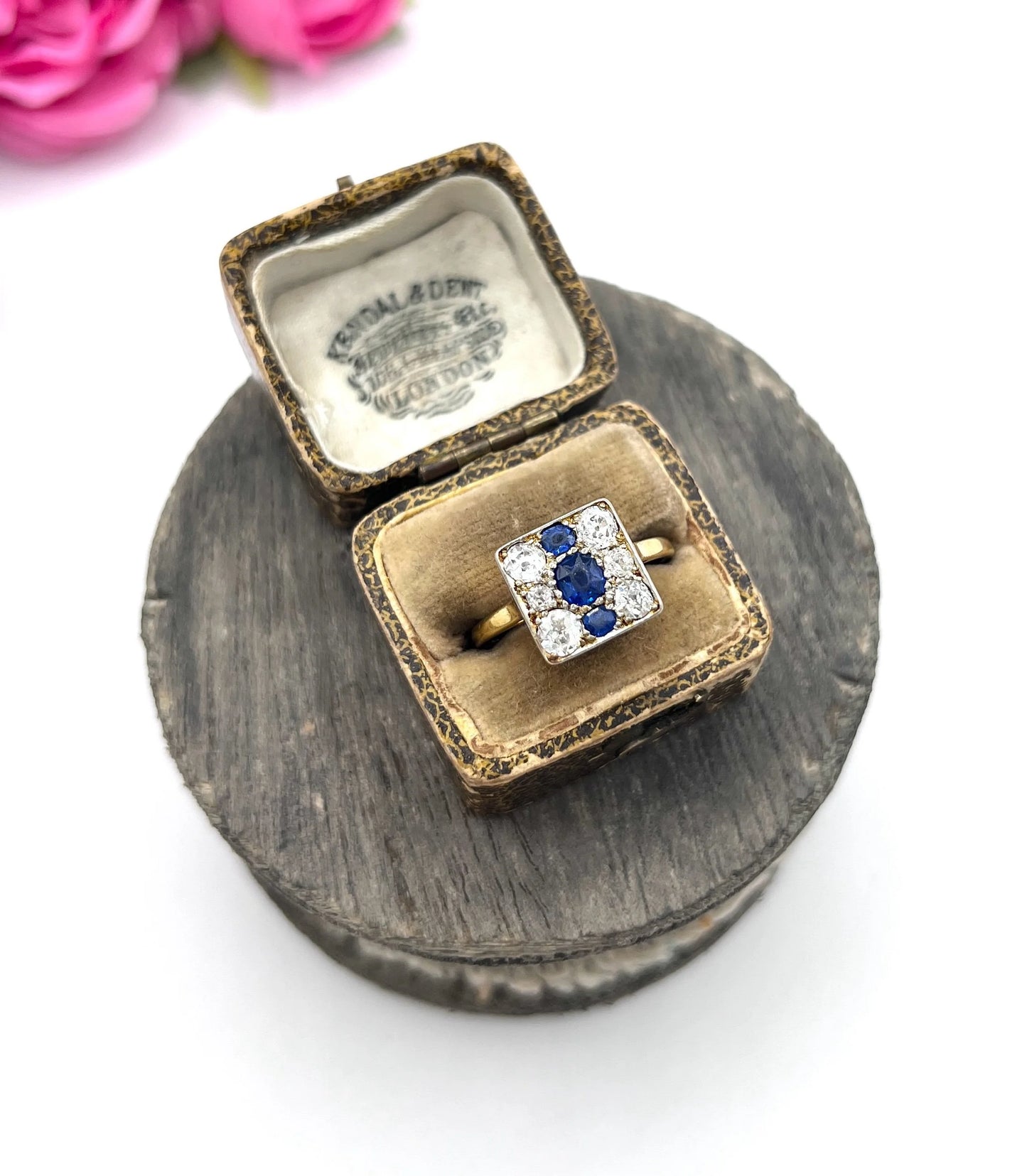 A square-shaped cluster ring with sapphires and diamonds in yellow gold and platinum, in an antique ring box