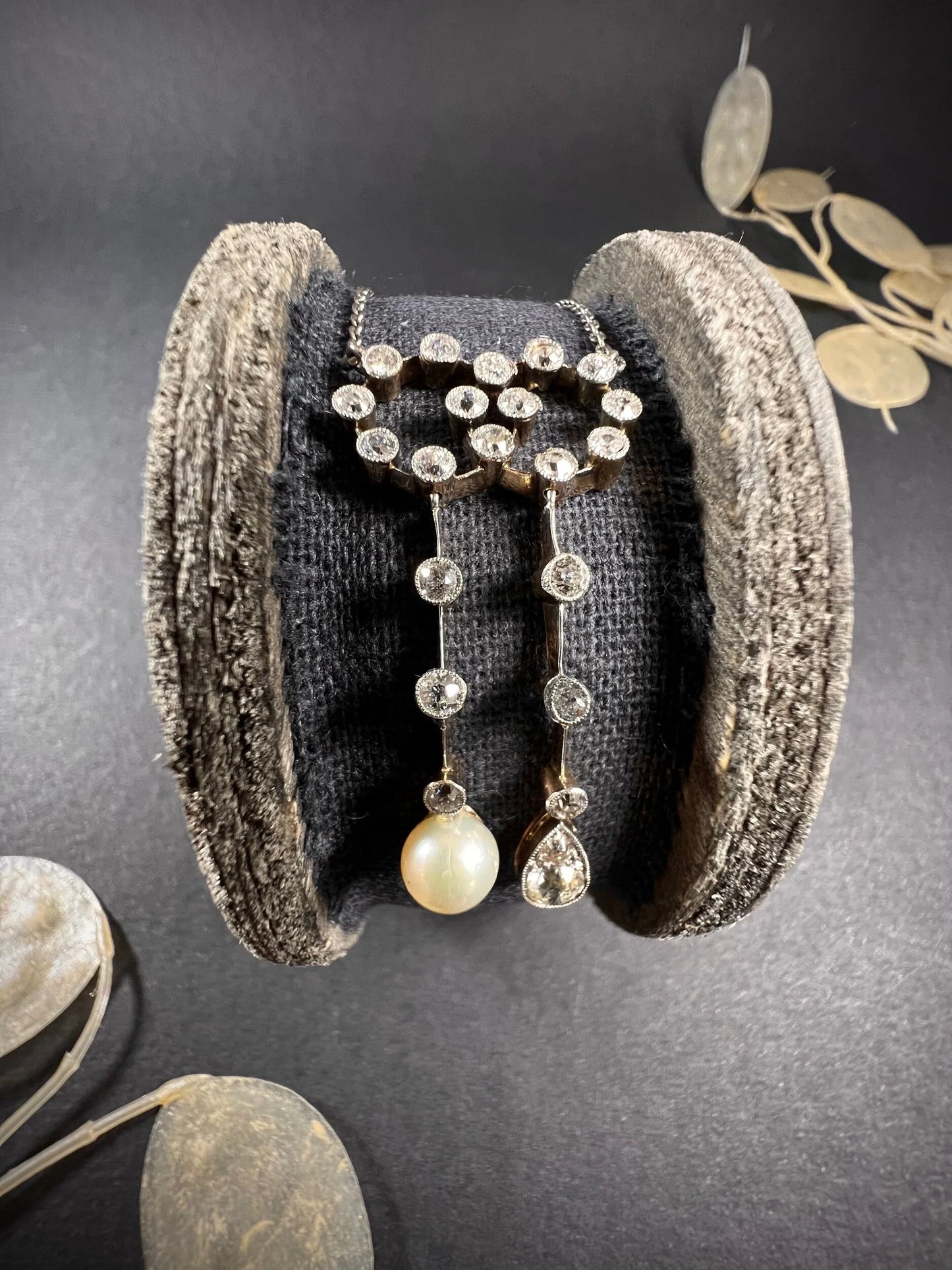 An antique diamond and pearl double drop pendant necklace, on a wooden spool