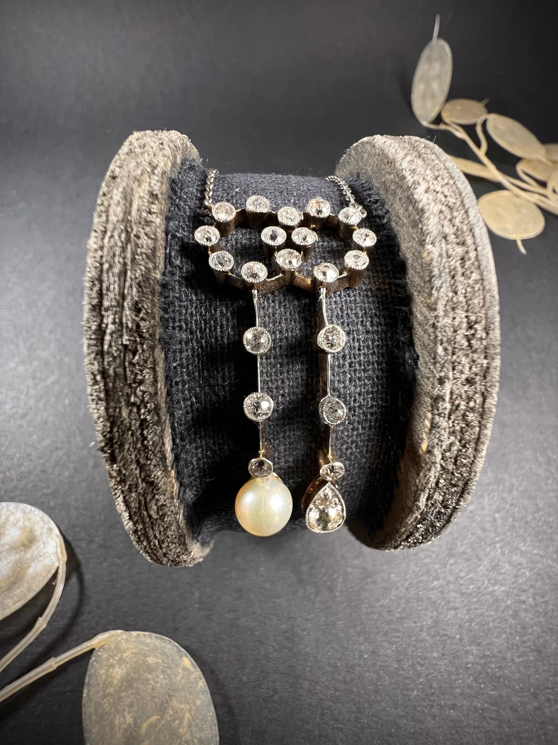 An antique diamond and pearl double drop pendant necklace, on a wooden spool