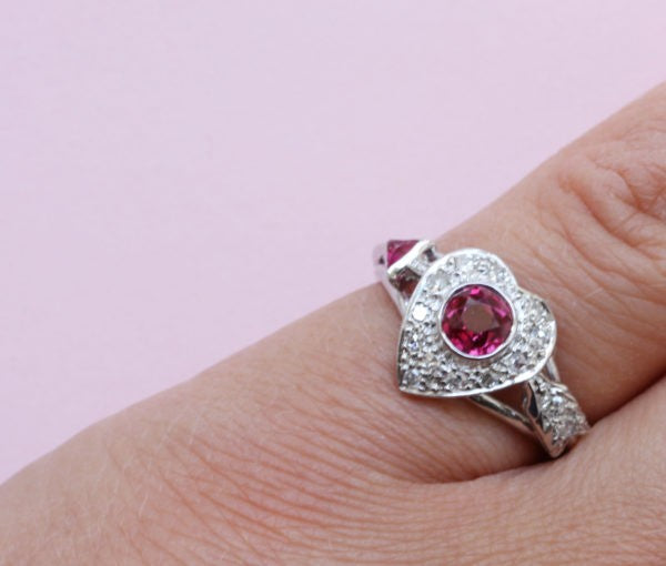 Vintage 1950s Ruby and Diamond Heart and Arrow Ring; 0.75ct round old-cut ruby surrounded by 0.30cts diamonds, in platinum and white gold