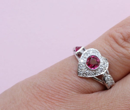 Vintage 1950s Ruby and Diamond Heart and Arrow Ring; 0.75ct round old-cut ruby surrounded by 0.30cts diamonds, in platinum and white gold
