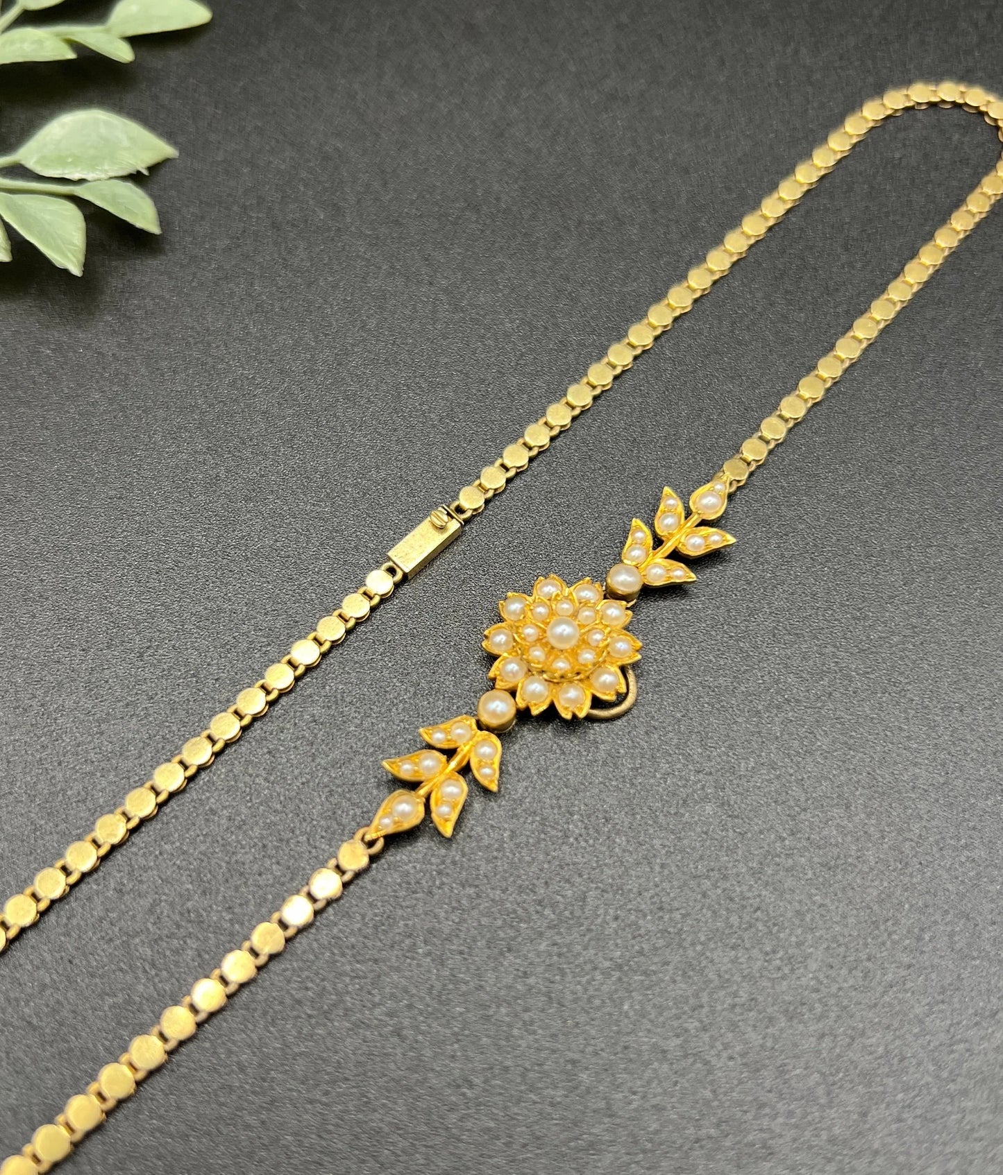 A yellow gold pearl floral necklace with integrated chain