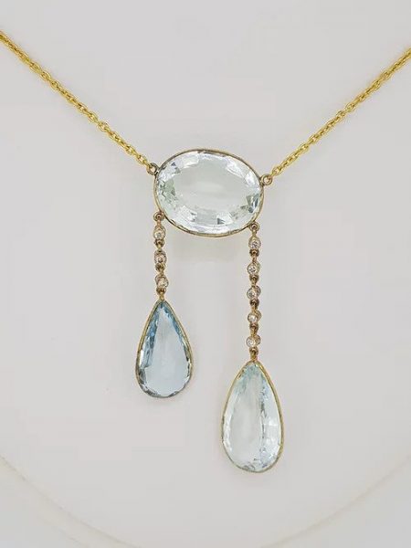 Aquamarine and Diamond Pendant; featuring a central oval faceted aquamarine suspending two pear shaped aquamarines via diamond set chains, 25.00 carat total, spectacle set in 18ct yellow gold