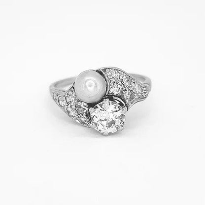 Belle Epoque Natural Pearl and Old Cut Diamond Ring; featuring an old cut diamond and grey natural pearl, diamond encrusted shoulders. Mounted in platinum with a pierced scrolled under-gallery