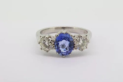 Sapphire and Diamond Three Stone Ring in Platinum; central 2.05 carat oval faceted sapphire flanked by 1.00cts round brilliant-cut diamonds