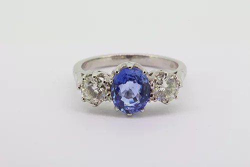 Sapphire and Diamond Three Stone Ring in Platinum; central 2.05 carat oval faceted sapphire flanked by 1.00cts round brilliant-cut diamonds