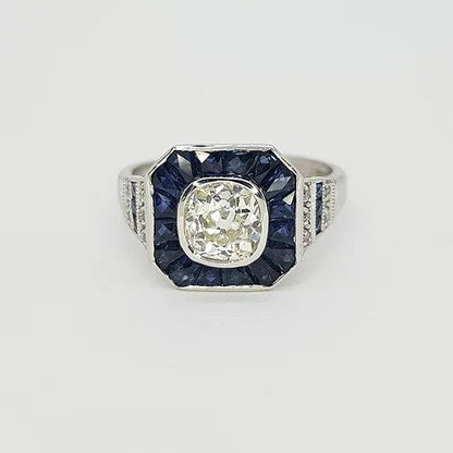 Sapphire and Diamond Calibre Cluster Target Ring; central 1.20 carat brilliant cut diamond surrounded by calibre cut sapphires, diamonds and sapphires set to the shoulders, in 18ct white gold. Reminiscent of the Art Deco style