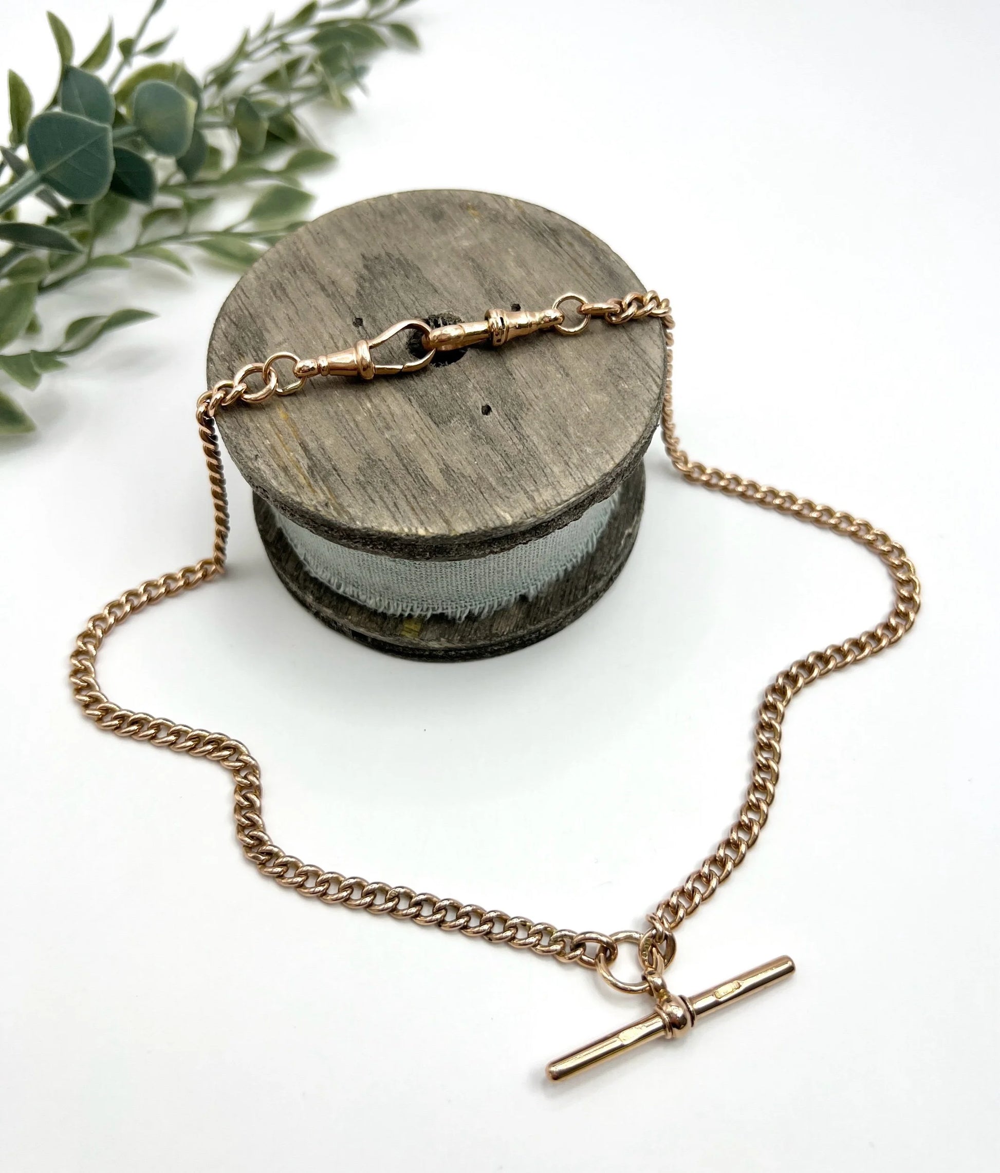A gold curb link Albert chain, laid on a wooden spool