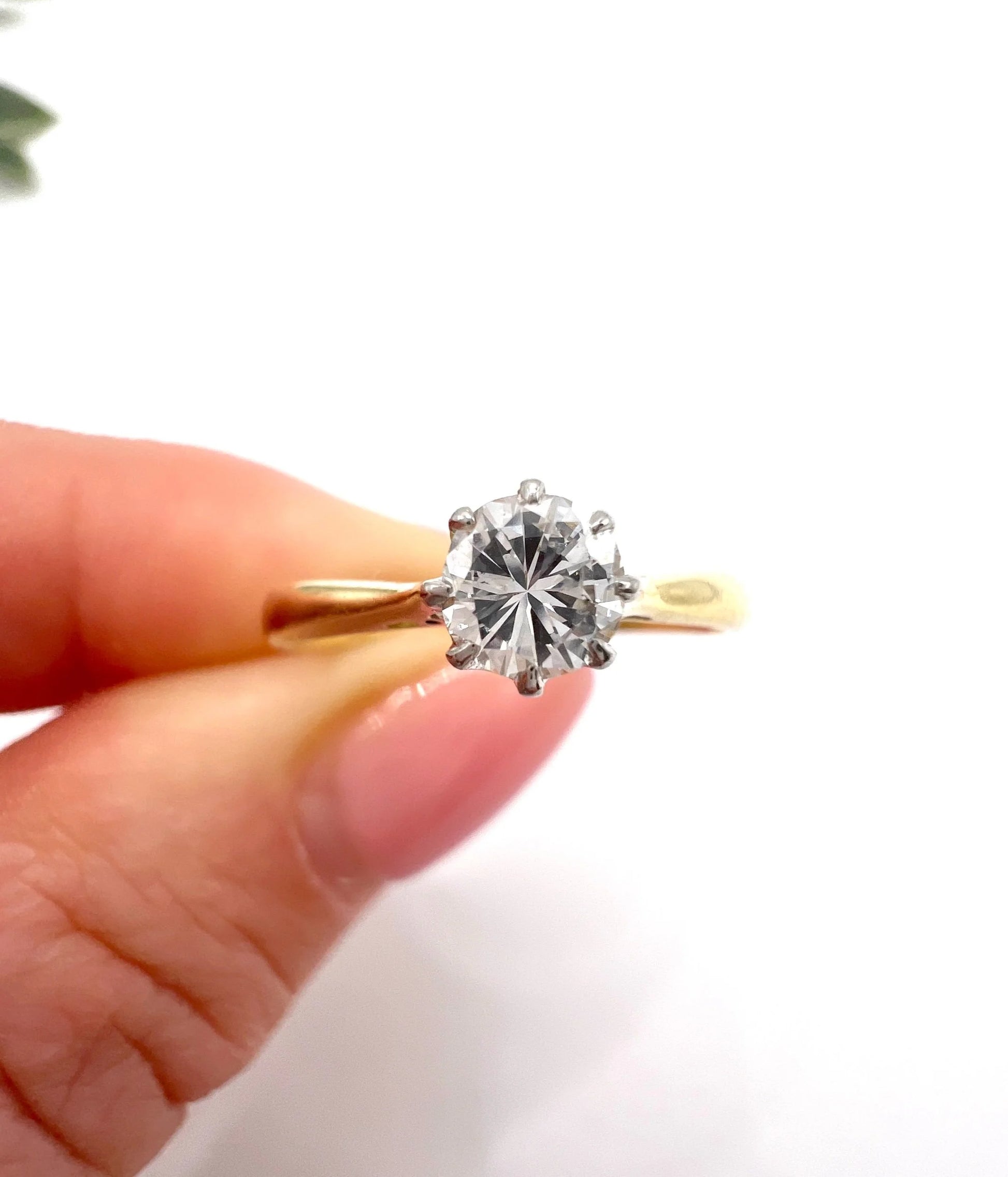 A single stone brilliant cut diamond ring claw set in platinum and yellow gold, held in a hand