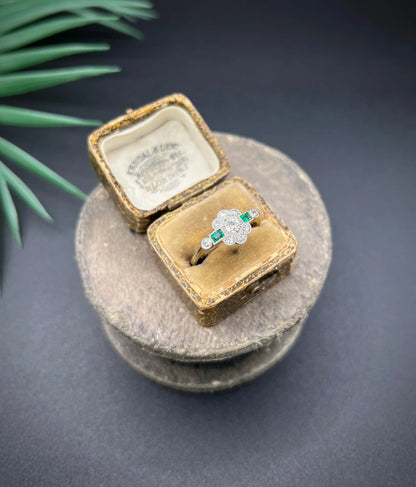 An emerald and diamond floral cluster ring in yellow gold and platinum, in an antique ring box
