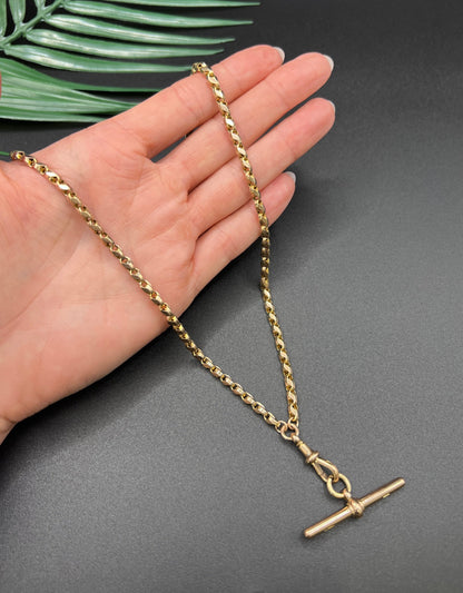 A rose gold tulip link chain necklace with a dog clip clasp and T-bar, held in a hand