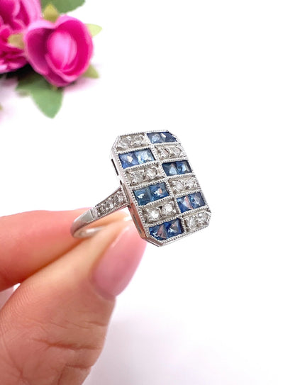 A sapphire and diamond tablet style ring in platinum, held in a hand