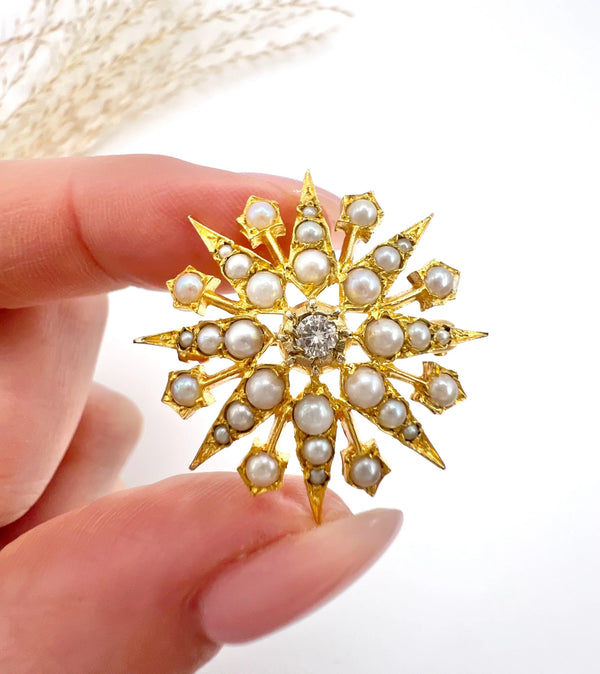 A star-shaped pearl and diamond brooch/pendant in yellow gold, held in a hand
