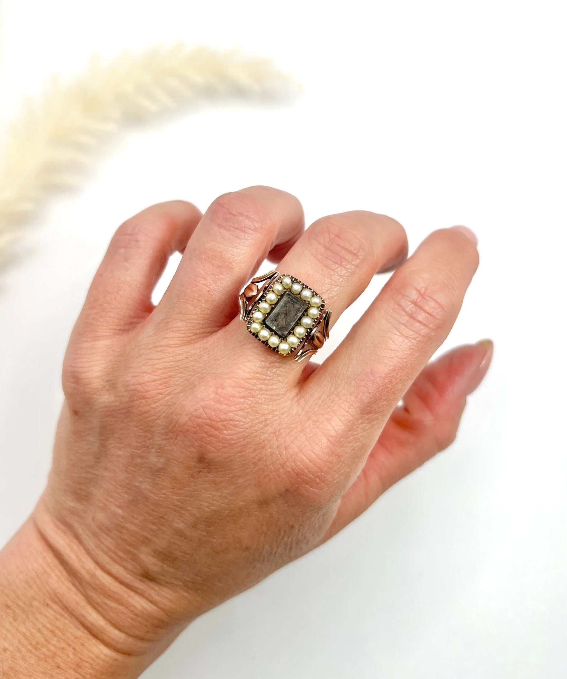An antique seed pearl mourning ring in gold, modelled on a hand