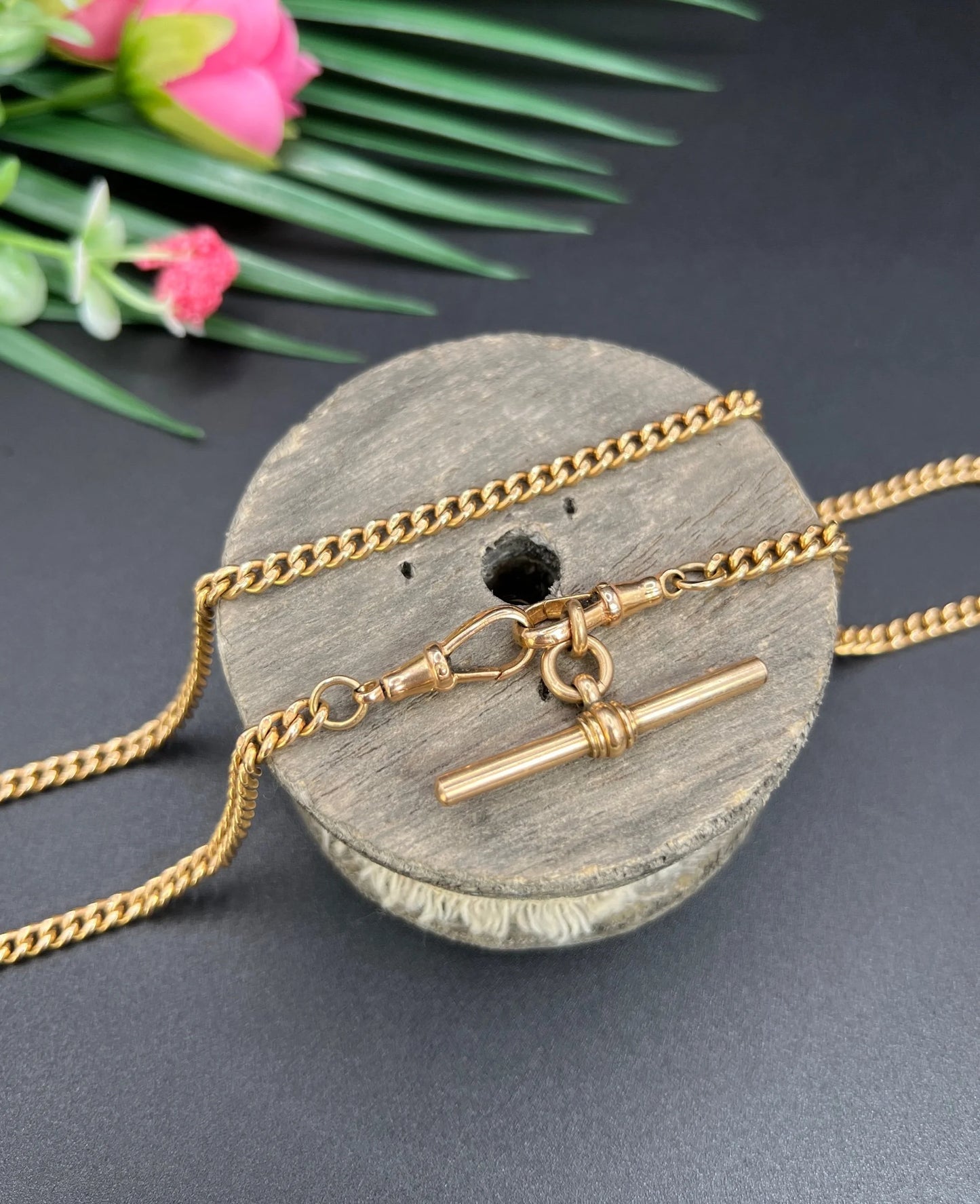 A gold curb link Albert chain, on a wooden spool