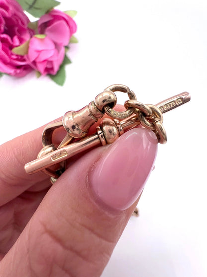 A rose gold fancy link Albert chain necklace, held in a hand