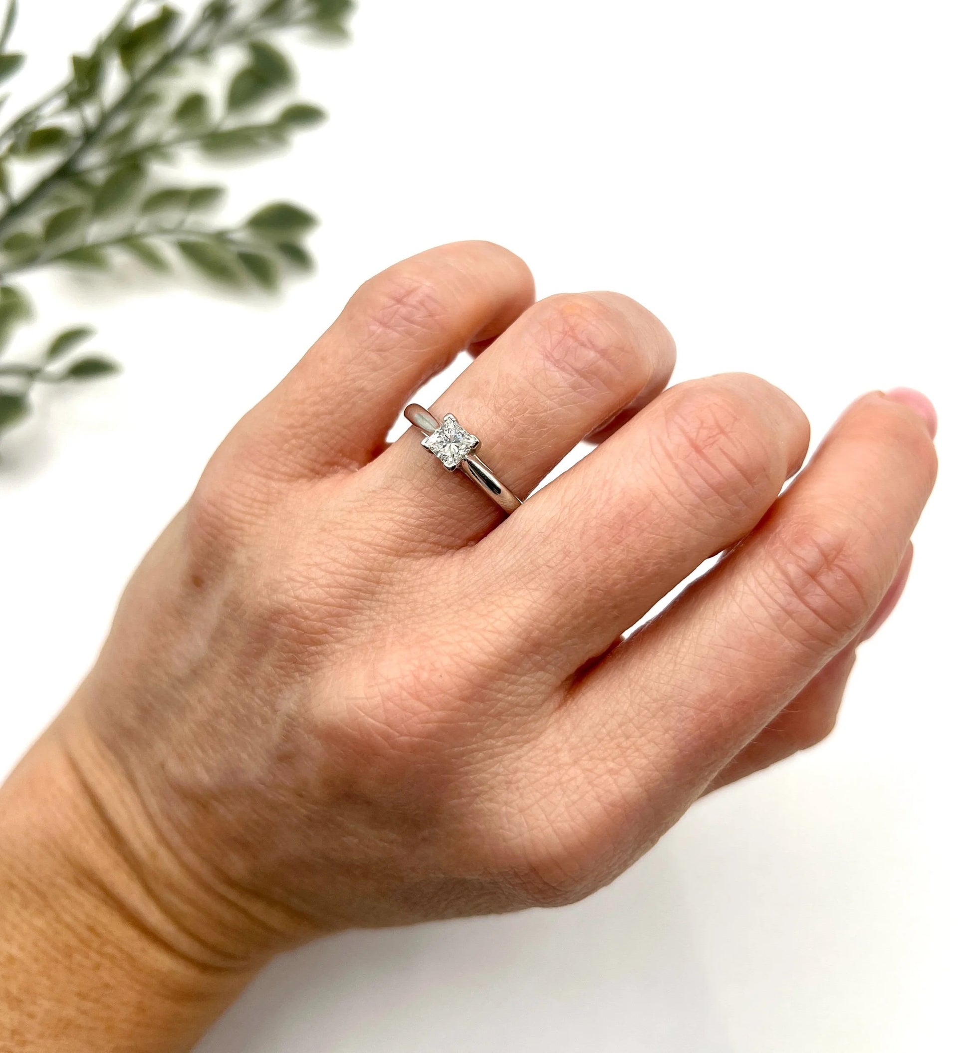 A princess cut diamond solitaire ring in platinum, modelled on a hand