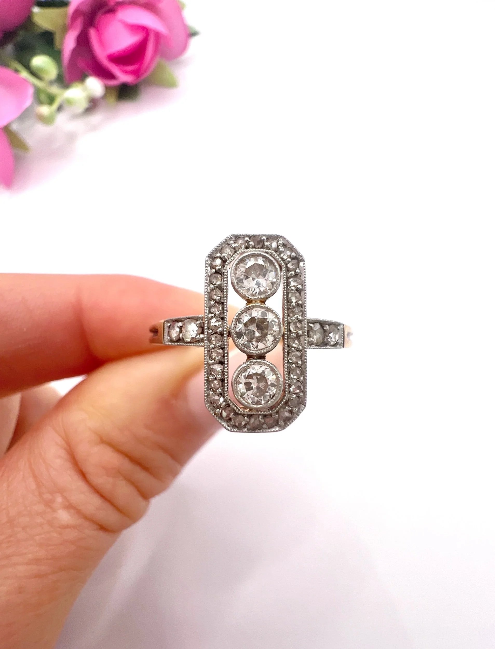 A diamond open cluster ring with three principal diamonds, in yellow and white gold, held in a hand