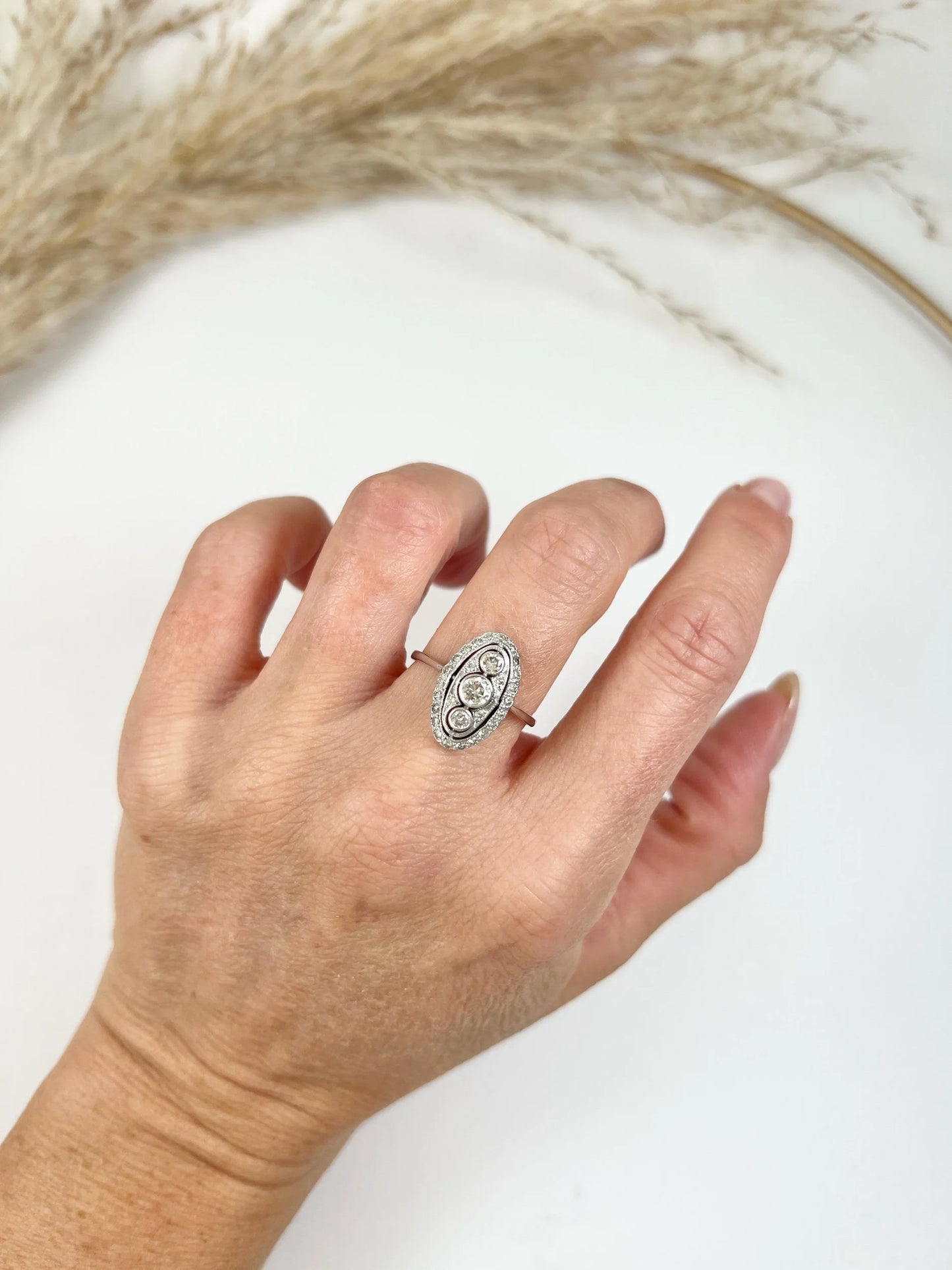 Antique 18 Carat White Gold Three Stone Diamond Oval Halo Ring, Circa 1910