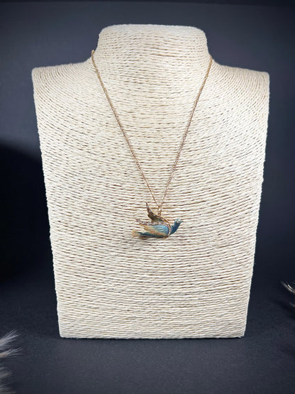 An enamel and diamond dove bird pendant, with a chain, on a jewellery display neck