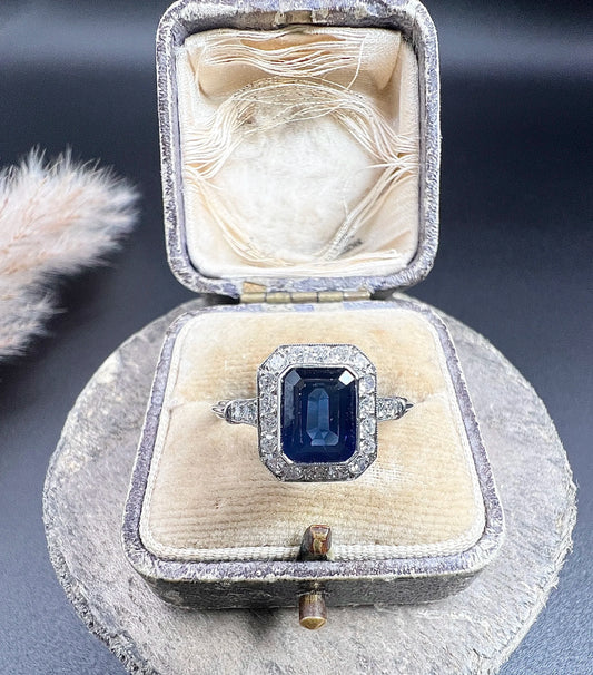 An octagonal cluster ring with sapphire and diamonds in white gold, in an antique ring box