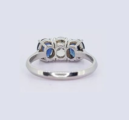 Sapphire and Diamond Three Stone Ring, classic trilogy ring featuring, 0.75ct oval-cut diamond flanked by 1.75cts oval sapphires, claw set, 18ct white gold.